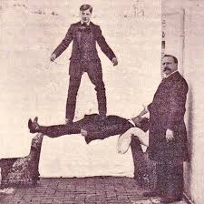 An old photo of a person standing of another in hypnosis